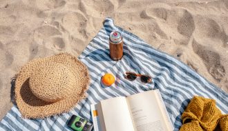 brown glass bottle beside white book on blue and white textile